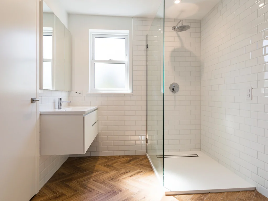 Petite salle de bain rénovée : sol à chevrons, faïence métro blanche et douche